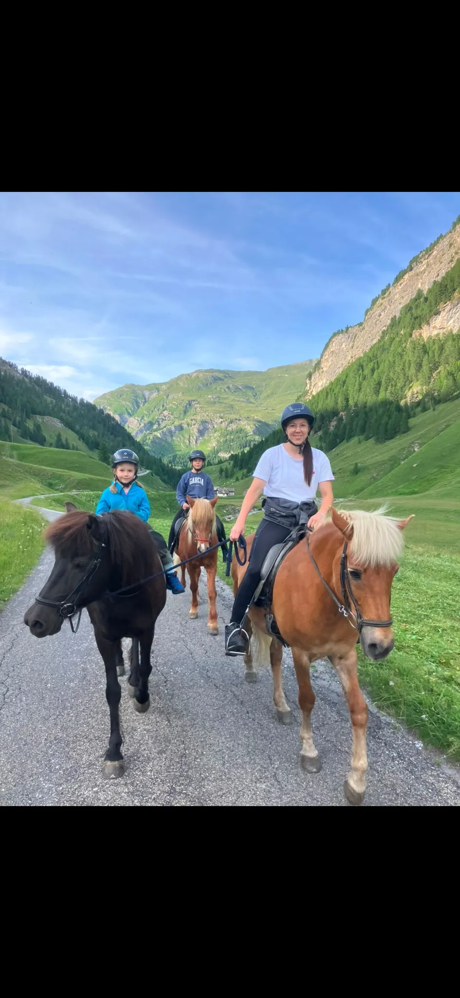 Cinzia reitet auf ihrem Pferd im Avers, im Hintergrund Berge und Wiesen